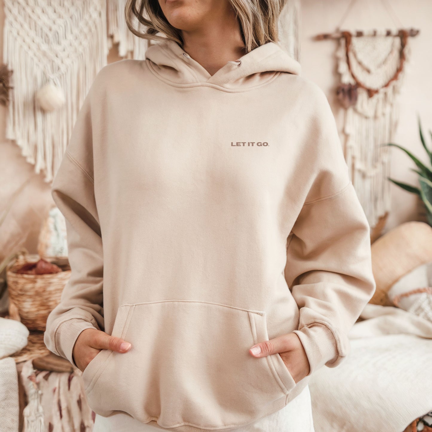 Model wearing sand oversized VIKA&EVE  LET IT GO hoodie indoor – minimalist unisex design for who we strive to be.